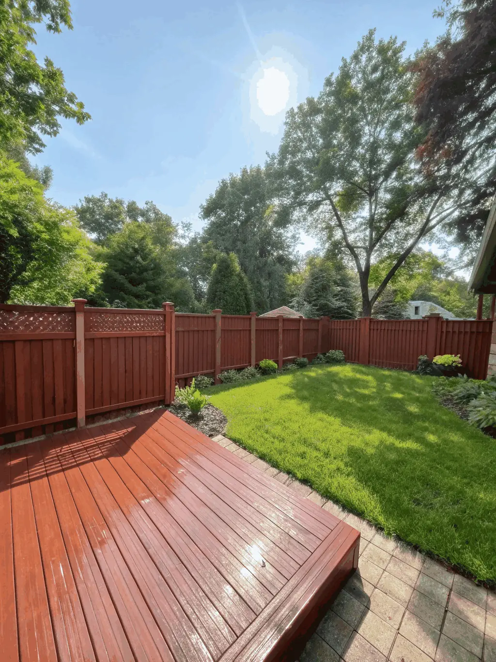 A clean wooden deck and fence with vibrant colors, free from dirt and algae, set in a sunny backyard in Louisville.